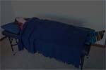 Reiki client lies on massage table with blanket, and lights are dimmed.